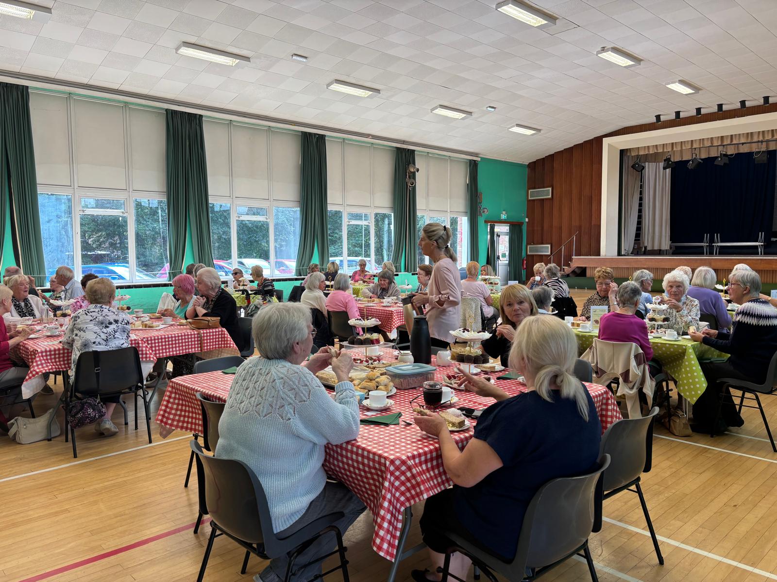 Lots of people sat having afternoon tea in large hall